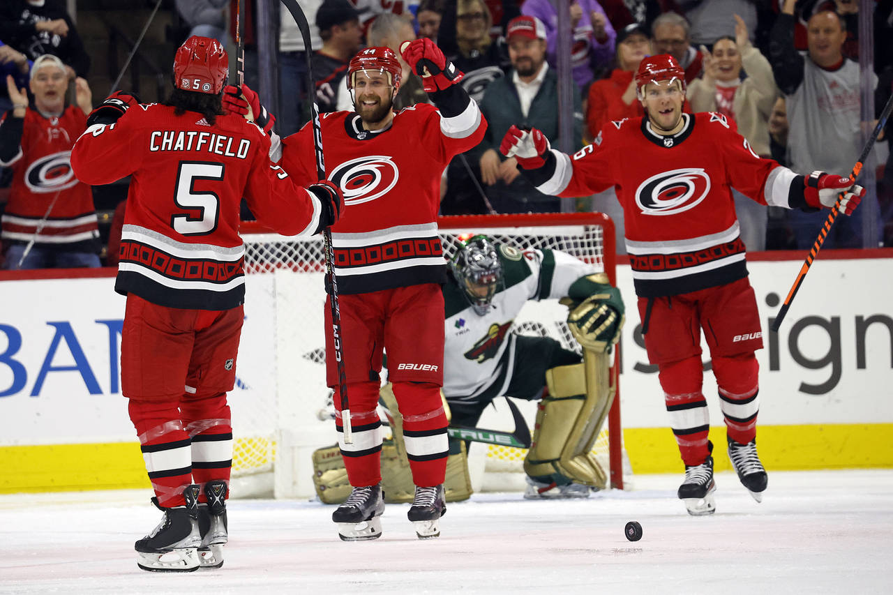 Carolina Hurricanes' Jalen Chatfield (5) celebrates his goal against the Minnesota Wild with Calvin...