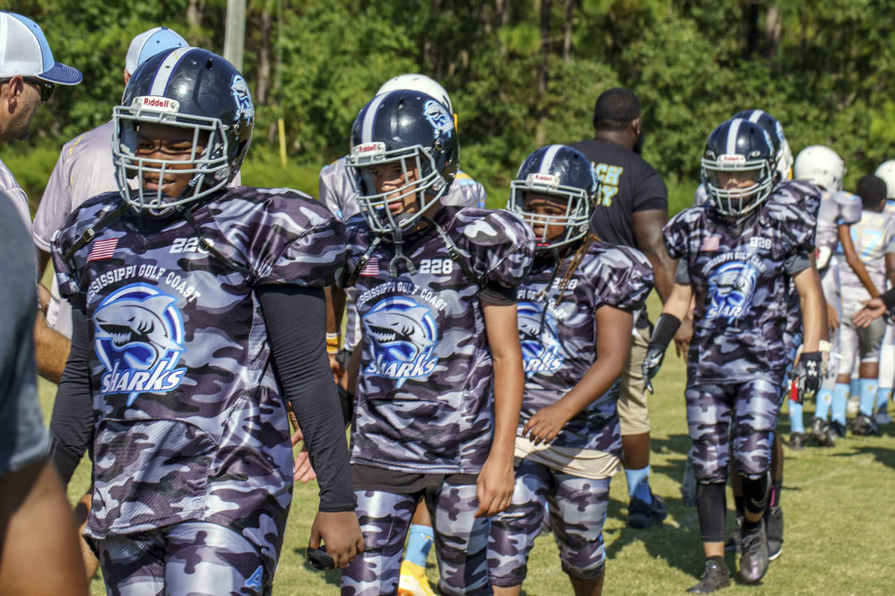 Youth players with the Gulf Coast Sharks Youth Football Club shake hands following a tackle footbal...