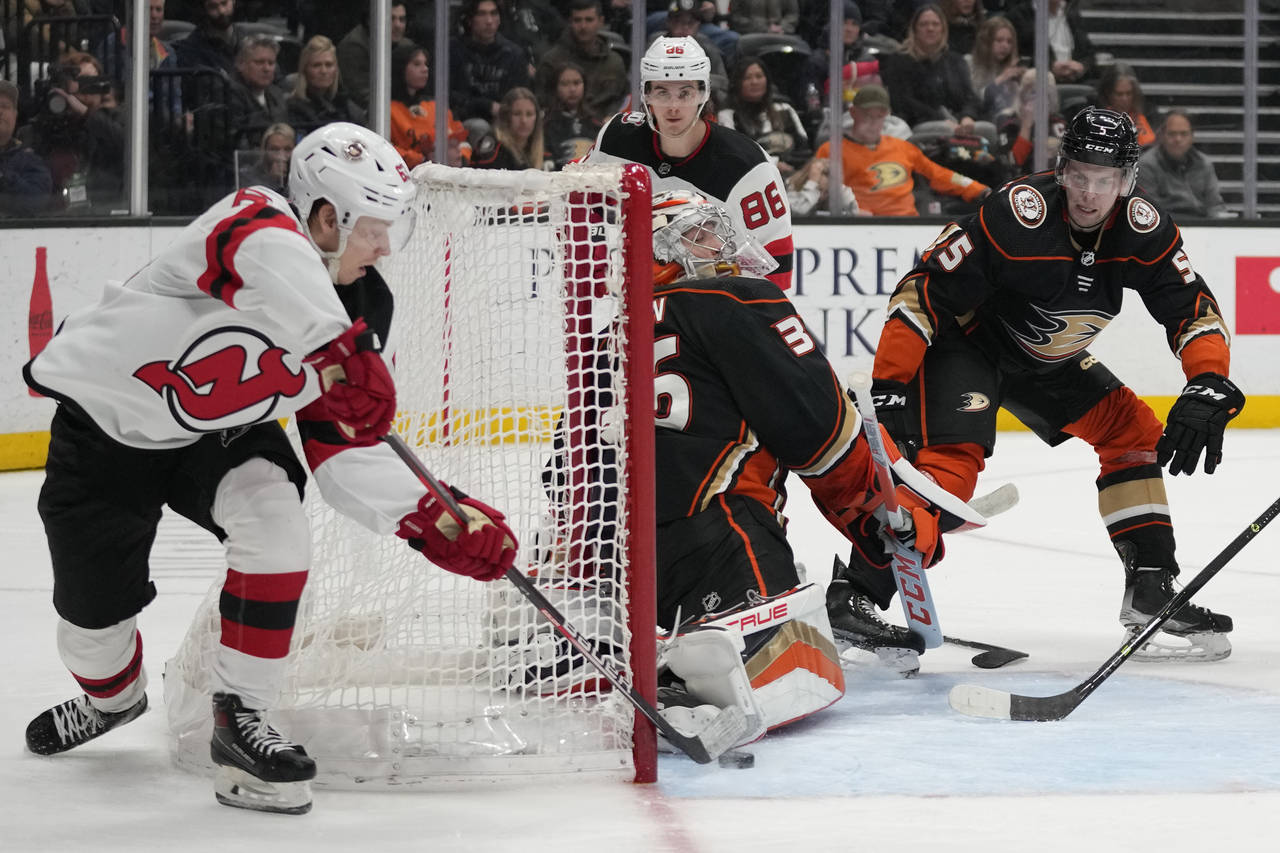 New Jersey Devils left wing Jesper Bratt, left, scores against Anaheim Ducks goaltender John Gibson...
