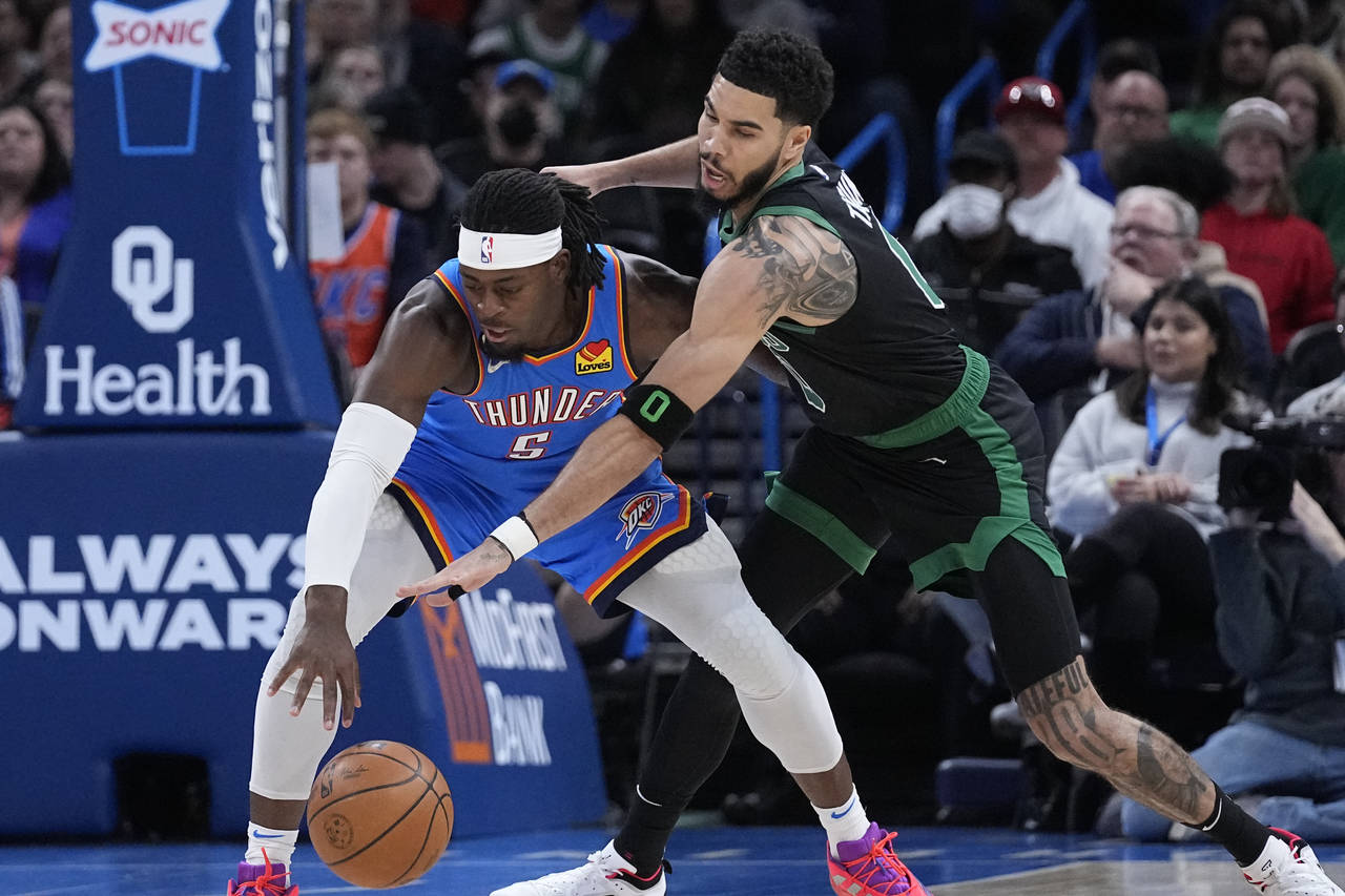 Boston Celtics forward Jayson Tatum, right, tries to knock the ball away from Oklahoma City Thunder...