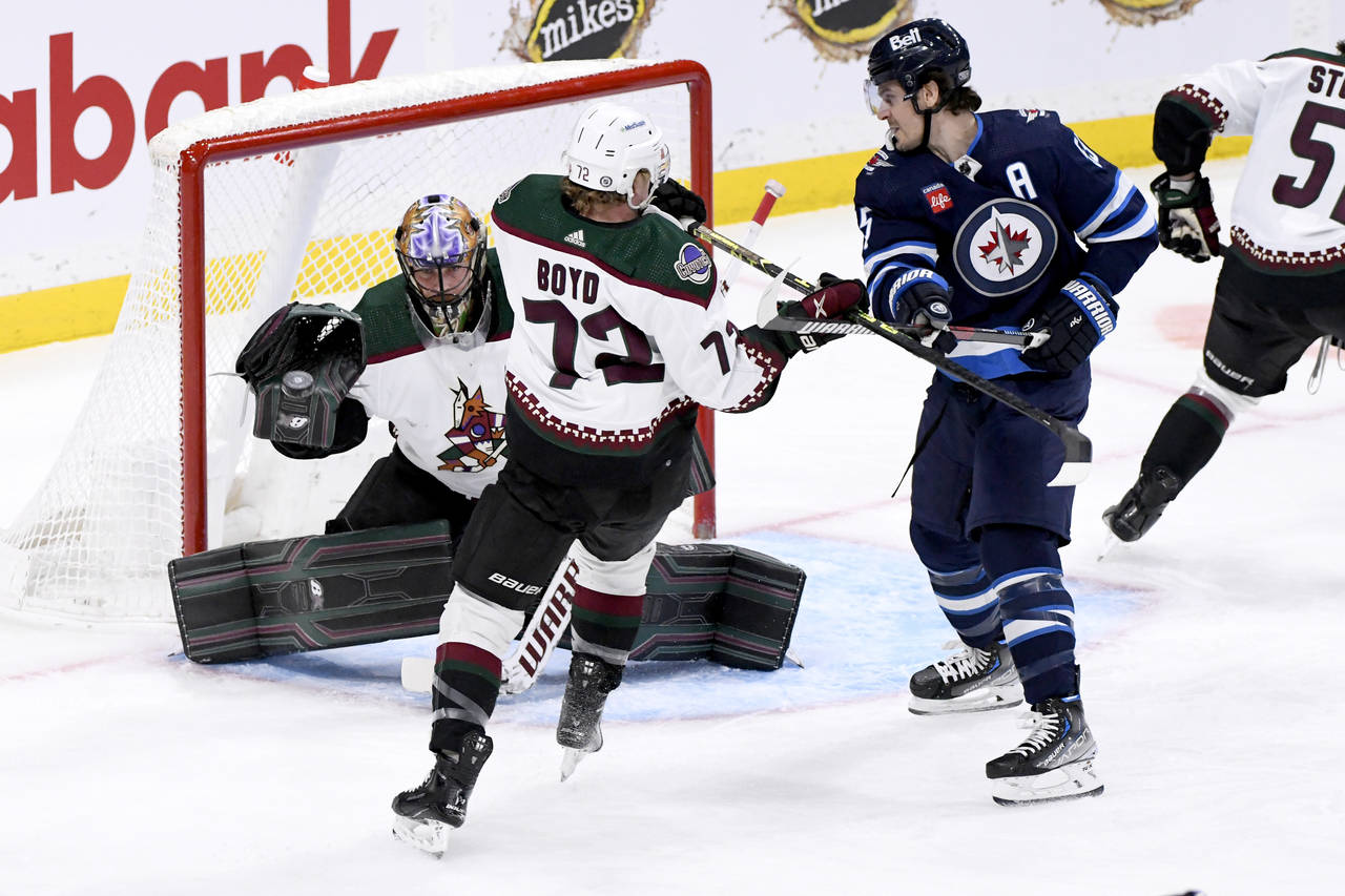 Arizona Coyotes goaltender Karel Vejmelka, left, makes a save against a Winnipeg Jets shot as Coyot...