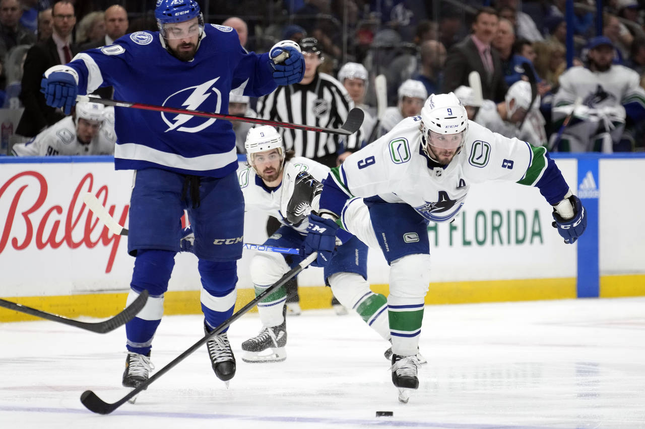 Vancouver Canucks center J.T. Miller (9) gets held by Tampa Bay Lightning left wing Nicholas Paul (...