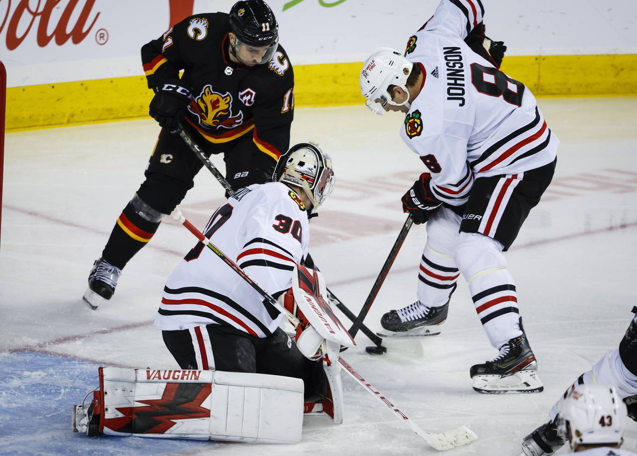 Chicago Blackhawks defenseman Jack Johnson, right, battles for the puck with Calgary Flames forward...