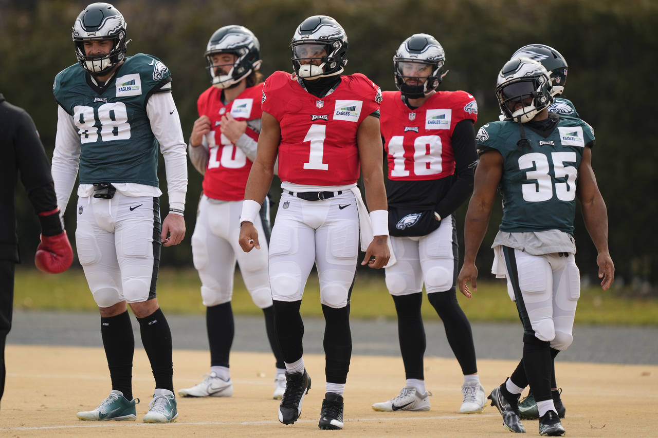 Philadelphia Eagles quarterback Jalen Hurts and teammates prepare to run a drill at the NFL footbal...