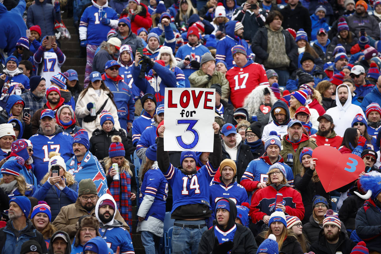 Fans hold signs in support of safety Damar Hamlin before an NFL football game against the New Engla...
