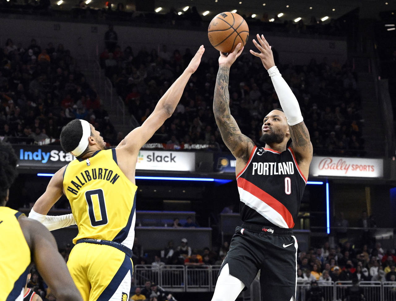 Portland Trail Blazers guard Damian Lillard, right, shoots over Indiana Pacers guard Tyrese Halibur...