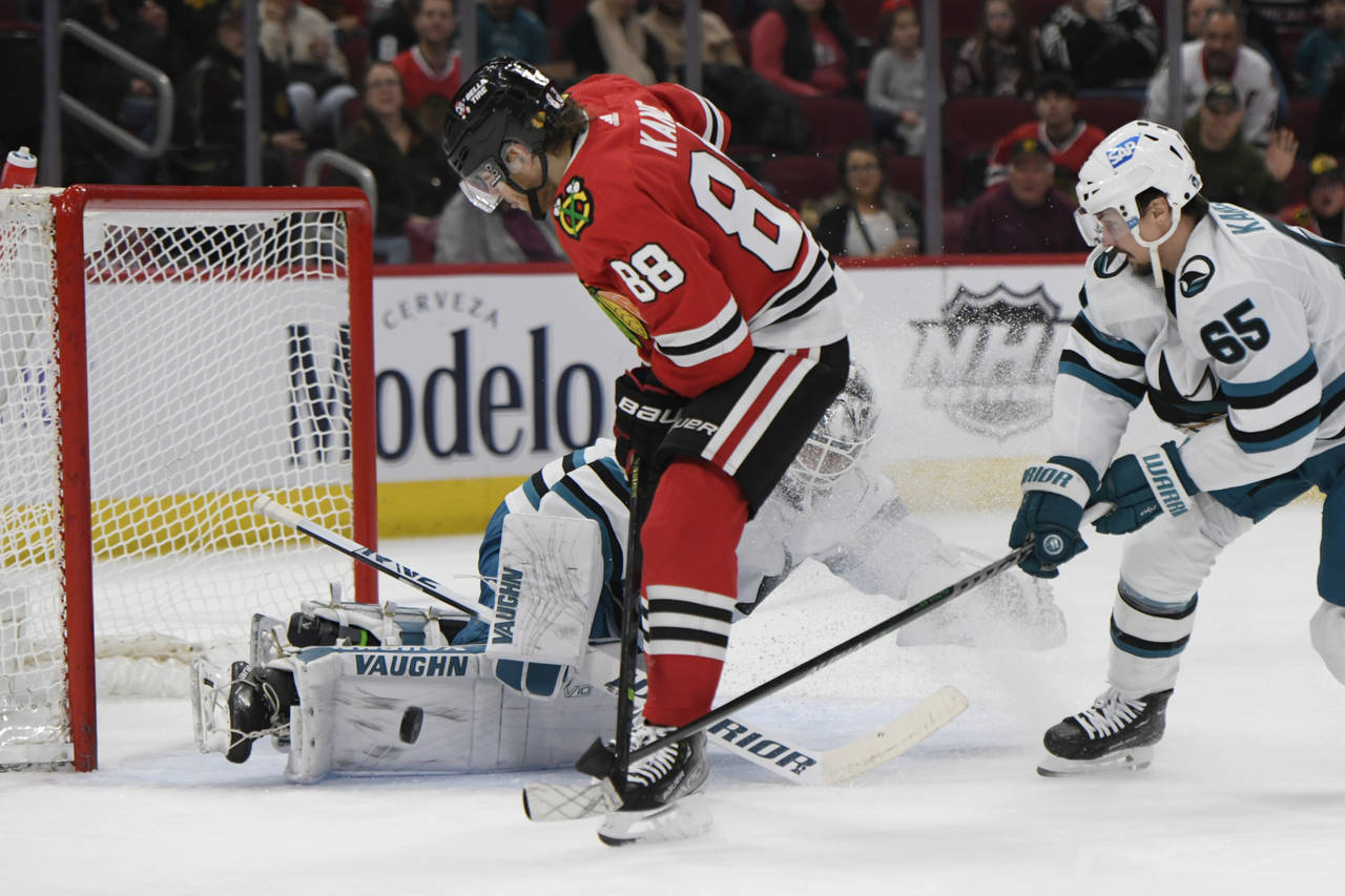 San Jose Sharks goalie Kaapo Kahkonen makes a save while teammate Erik Karlsson (65) battles Chicag...