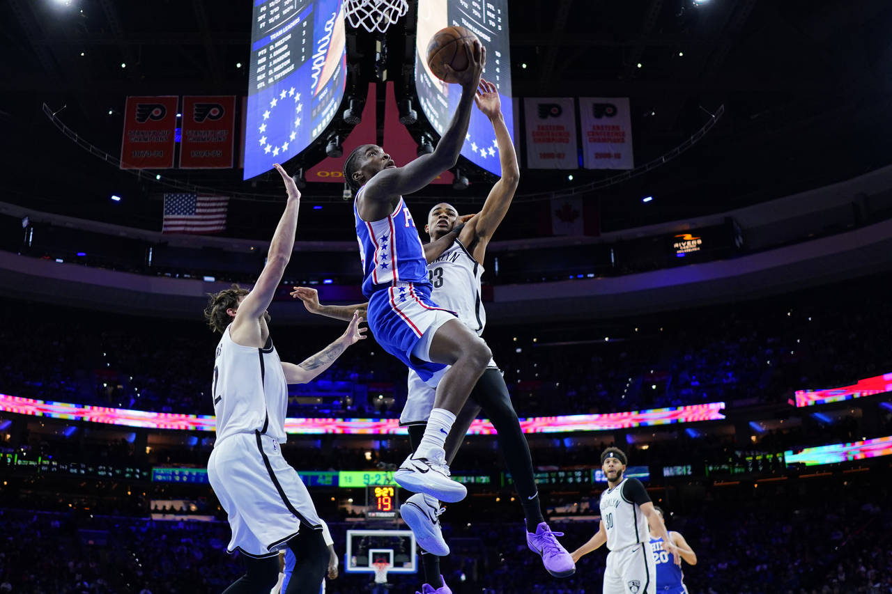 Philadelphia 76ers' Shake Milton, center, goes up for a shot between Brooklyn Nets' Joe Harris, lef...