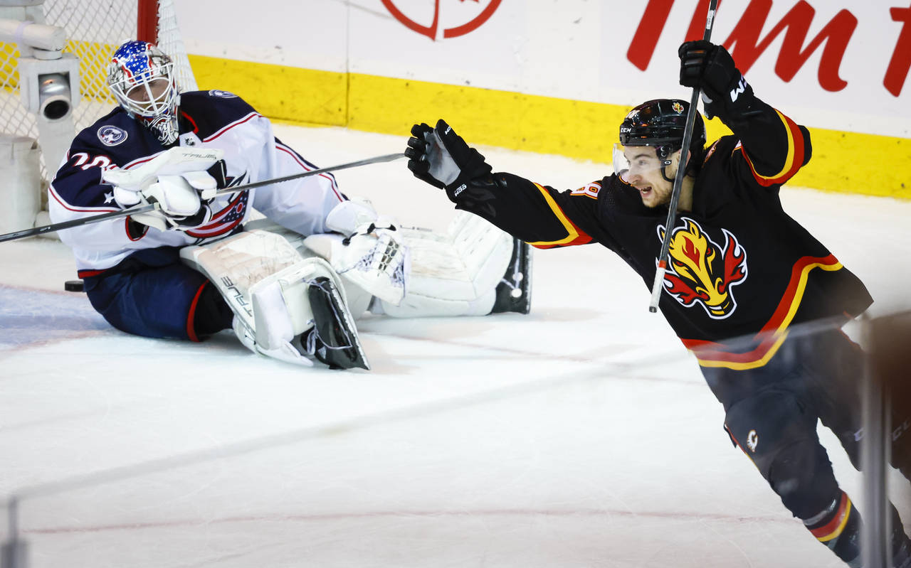 Columbus Blue Jackets goalie Joonas Korpisalo, left, looks on as Calgary Flames forward Andrew Mang...