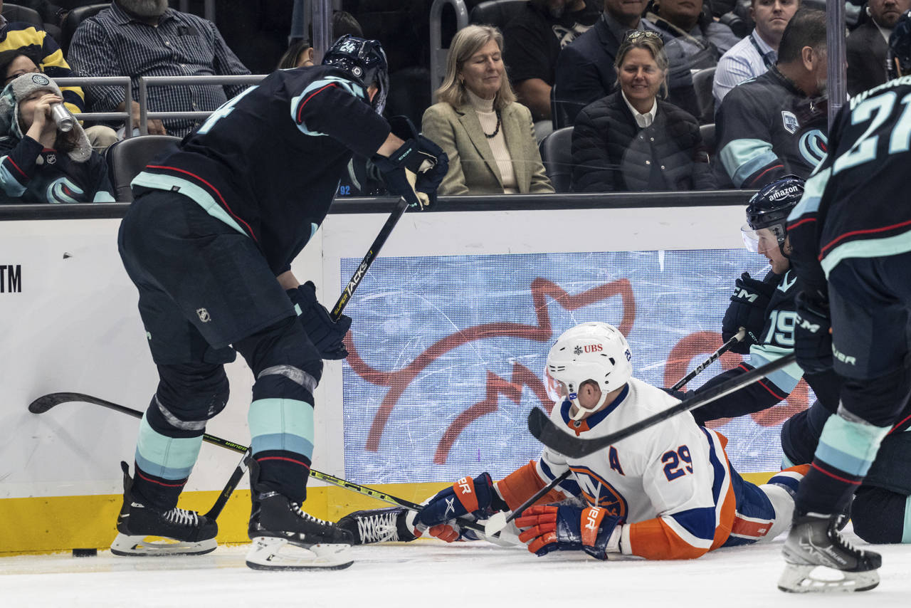 New York Islanders forward Brock Nelson, center, fights for the puck against Seattle Kraken defense...