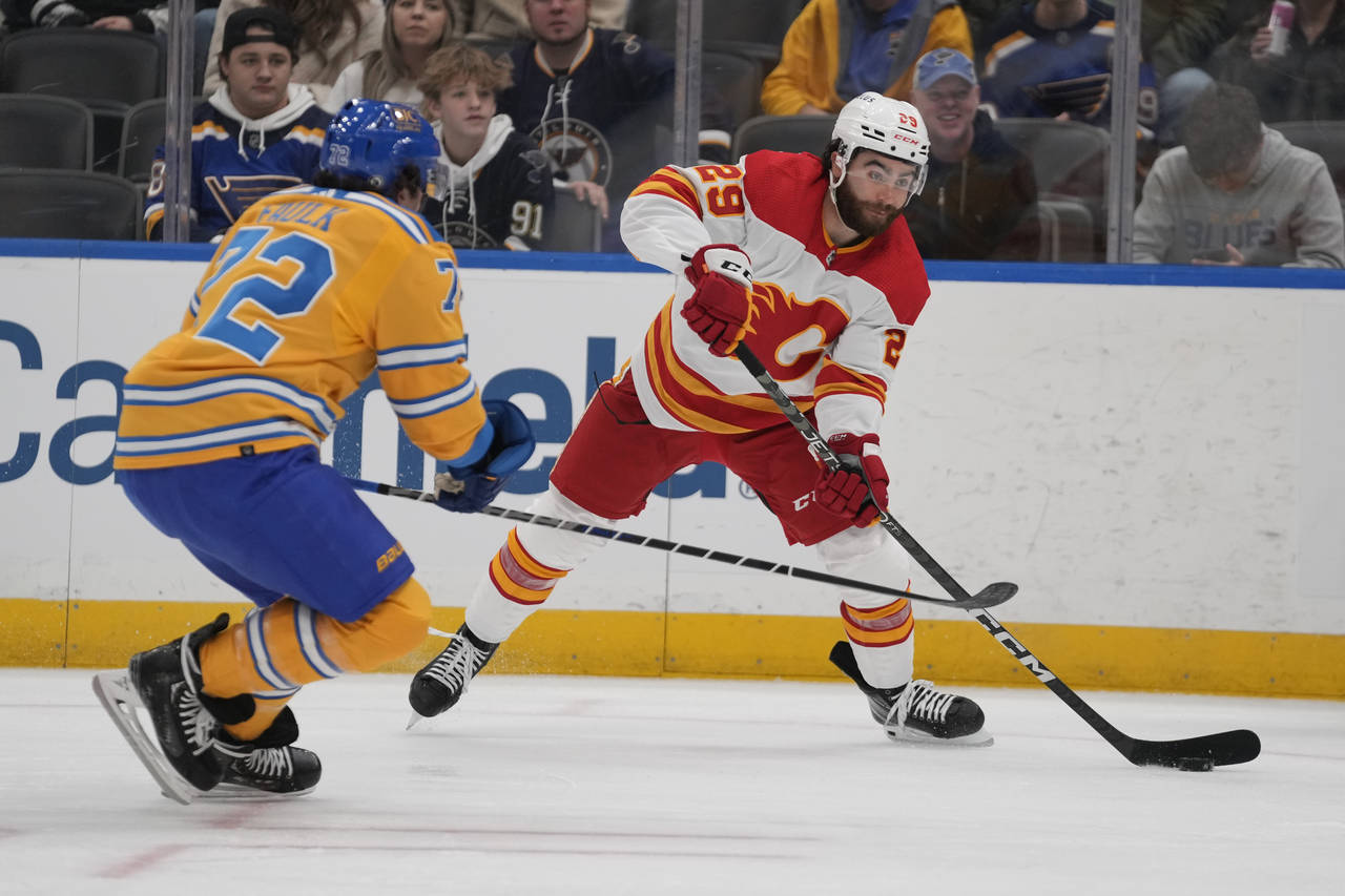 Calgary Flames' Dillon Dube (29) passes around St. Louis Blues' Justin Faulk (72) during the first ...
