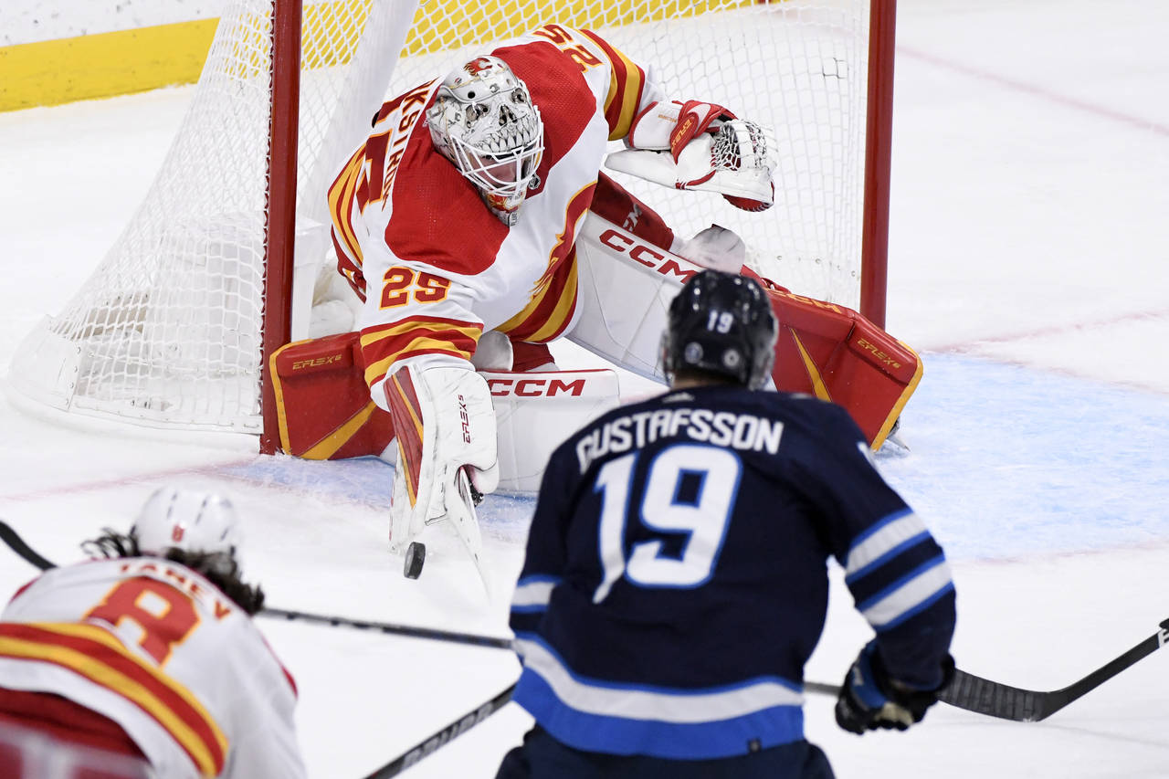 Calgary Flames goaltender Jacob Markstrom (25) makes a save on Winnipeg Jets' David Gustafsson (19)...