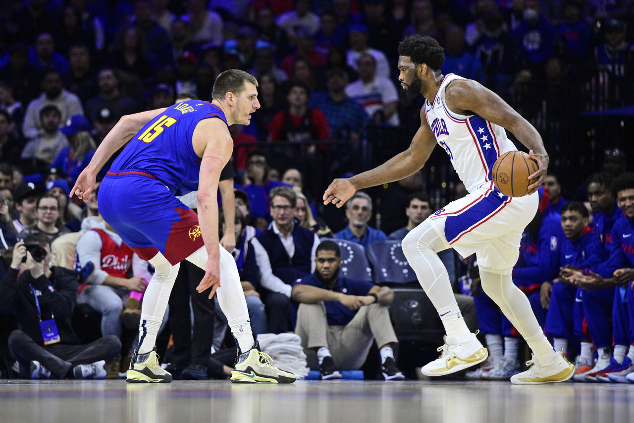 Philadelphia 76ers' Joel Embiid, right, dribbles the ball as Denver Nuggets' Nikola Jokic defends d...