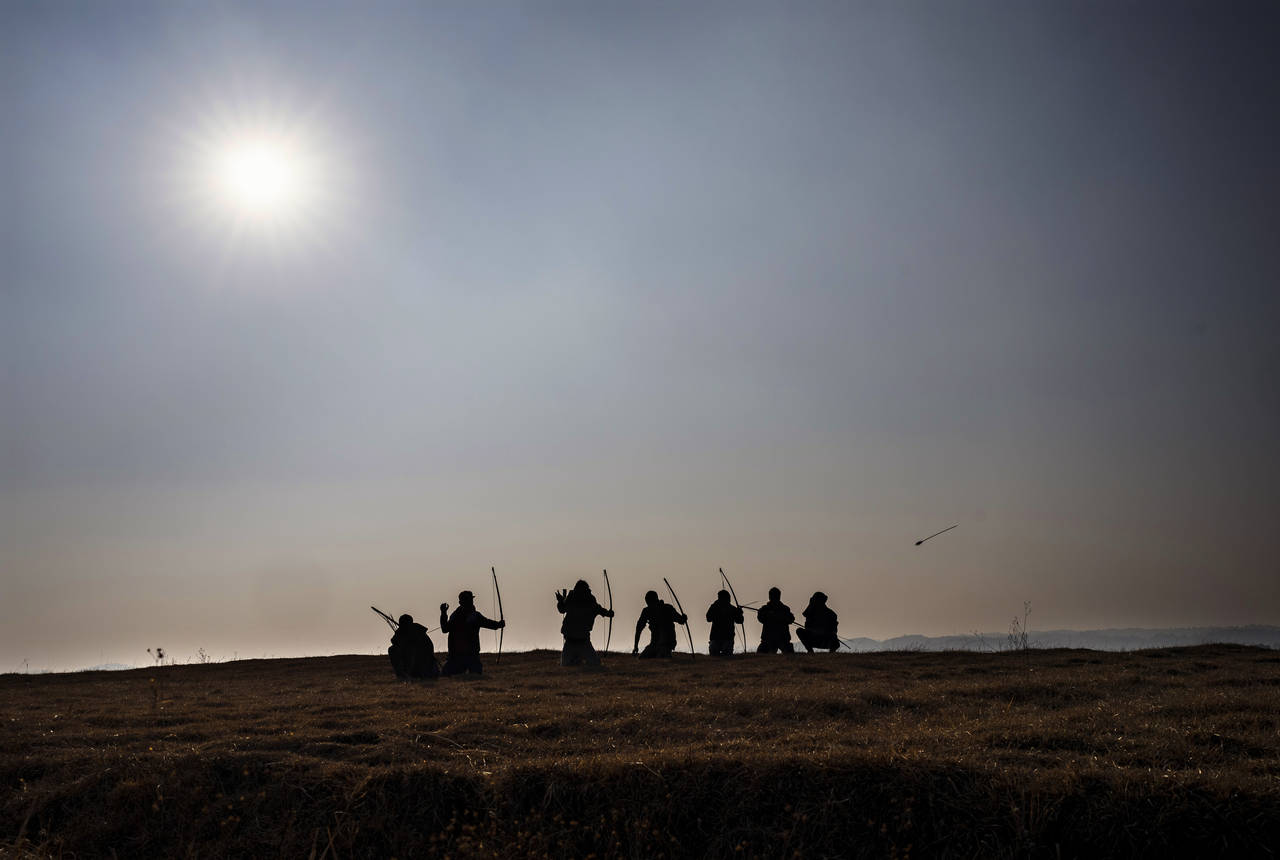 A group of local archers are silhouetted against the afternoon sun on a ridge overlooking the Laitl...