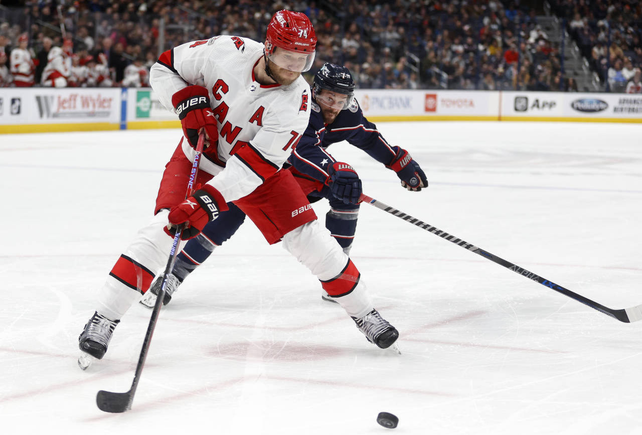 Carolina Hurricanes defenseman Jaccob Slavin, left, reaches for the puck in front of Columbus Blue ...