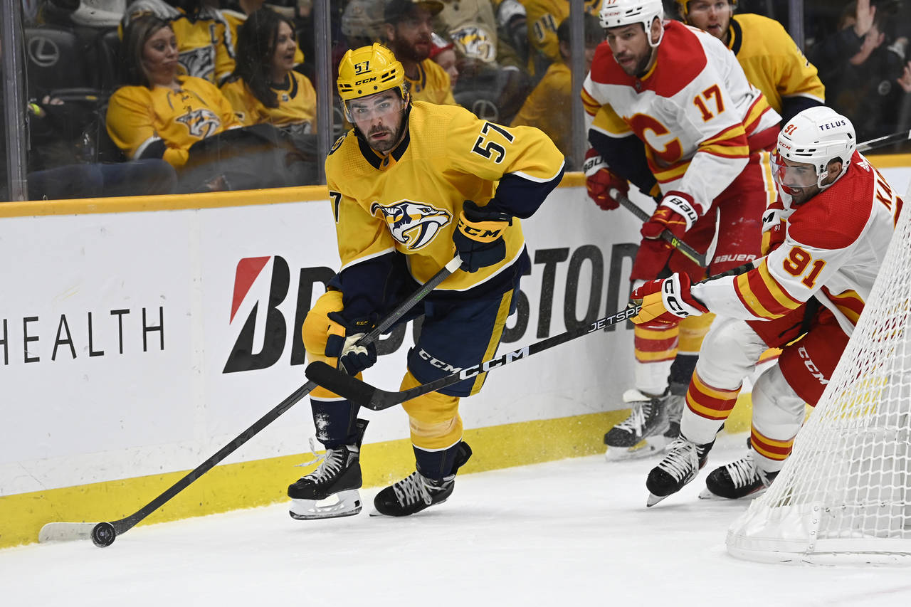 Nashville Predators defenseman Dante Fabbro (57) moves the puck ahead of Calgary Flames center Naze...