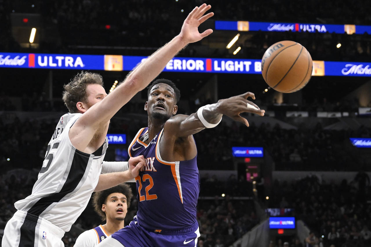 Phoenix Suns' Deandre Ayton (22) and San Antonio Spurs' Jakob Poeltl, left, grab for a rebound duri...