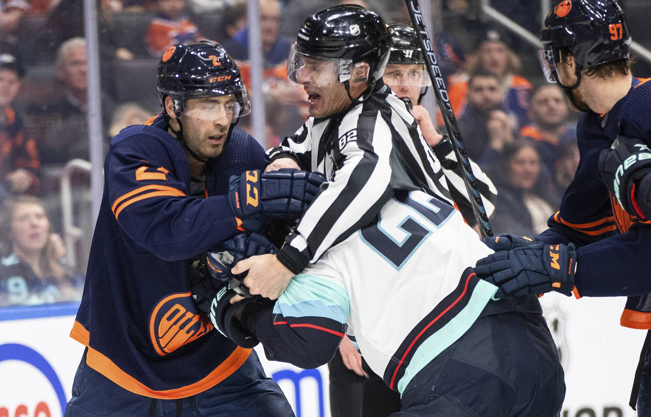 Seattle Kraken' Oliver Bjorkstrand (22) and Edmonton Oilers' Evan Bouchard (2) rough it up during t...