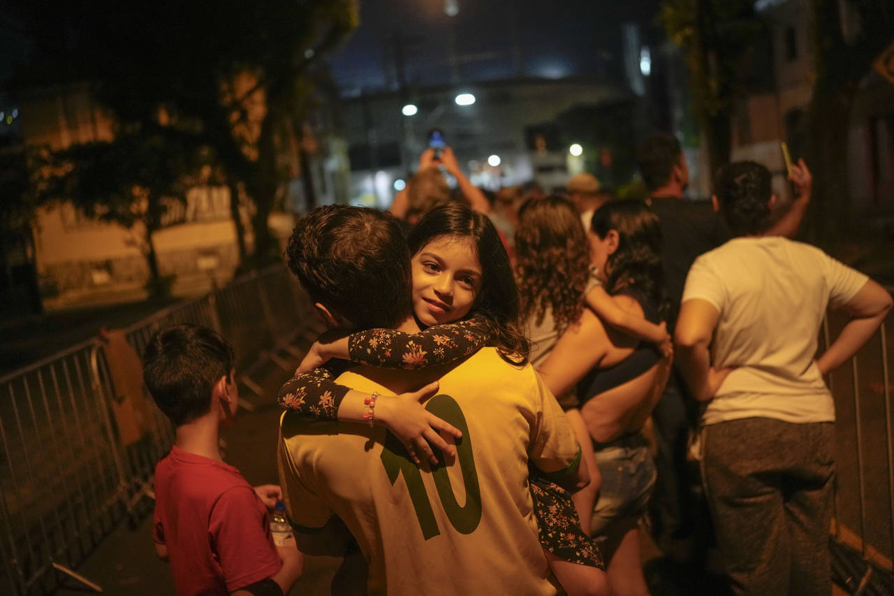 A man holds his daughter as he lines up to pay his last respects to the late Brazilian soccer legen...
