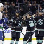 
              Seattle Kraken right wing Oliver Bjorkstrand (22) is congratulated by right wing Eeli Tolvanen (20) and defenseman Adam Larsson, second from right, after scoring against the Vancouver Canucks during the first period of an NHL hockey game, Wednesday, Jan. 25, 2023, in Seattle. (AP Photo/John Froschauer)
            
