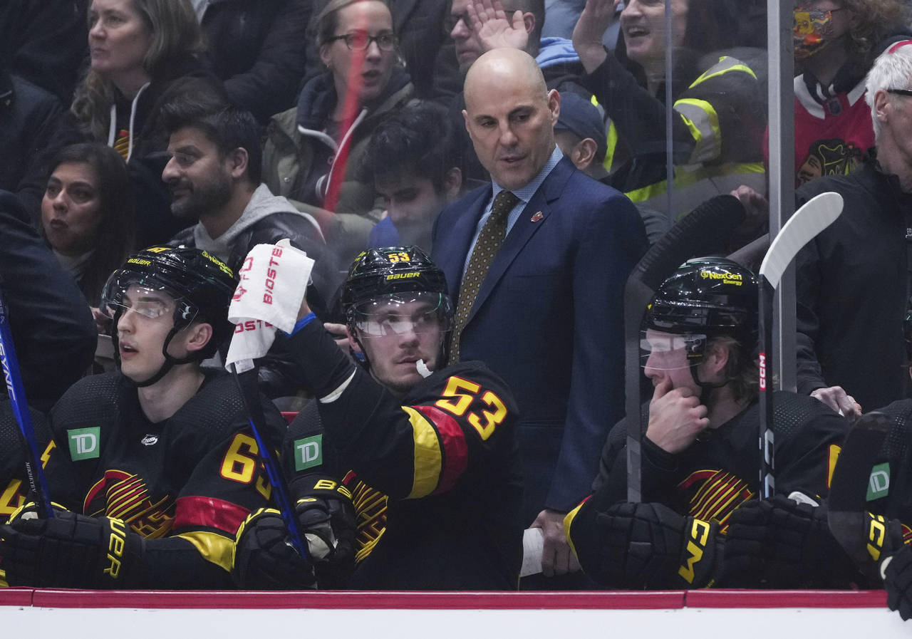 Vancouver Canucks coach Rick Tocchet, back, stands behind Ilya Mikheyev, Bo Horvat and Brock Boeser...