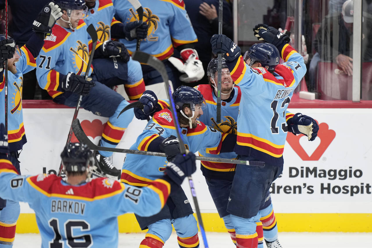 Florida Panthers center Sam Reinhart (13) is mobbed by teammates after he scored during an overtime...