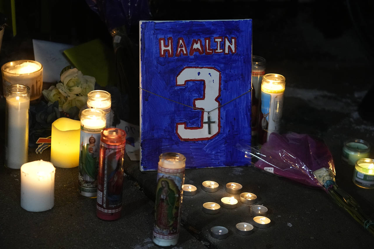 A painting that shows the number of Buffalo Bills' Damar Hamlin is illuminated by candles during a ...