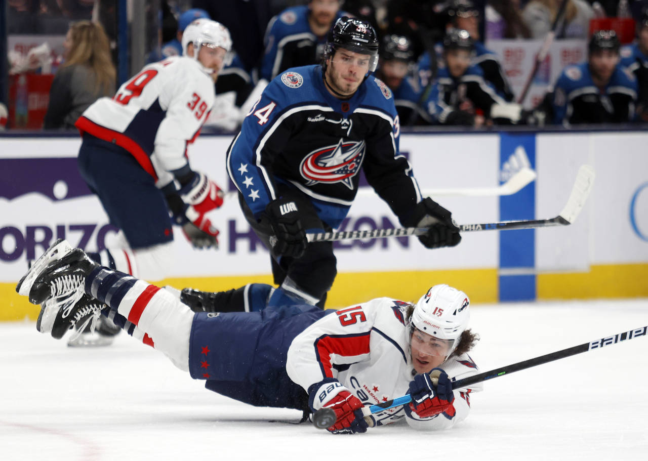 Washington Capitals forward Sonny Milano, right, dives for the puck in front of Columbus Blue Jacke...
