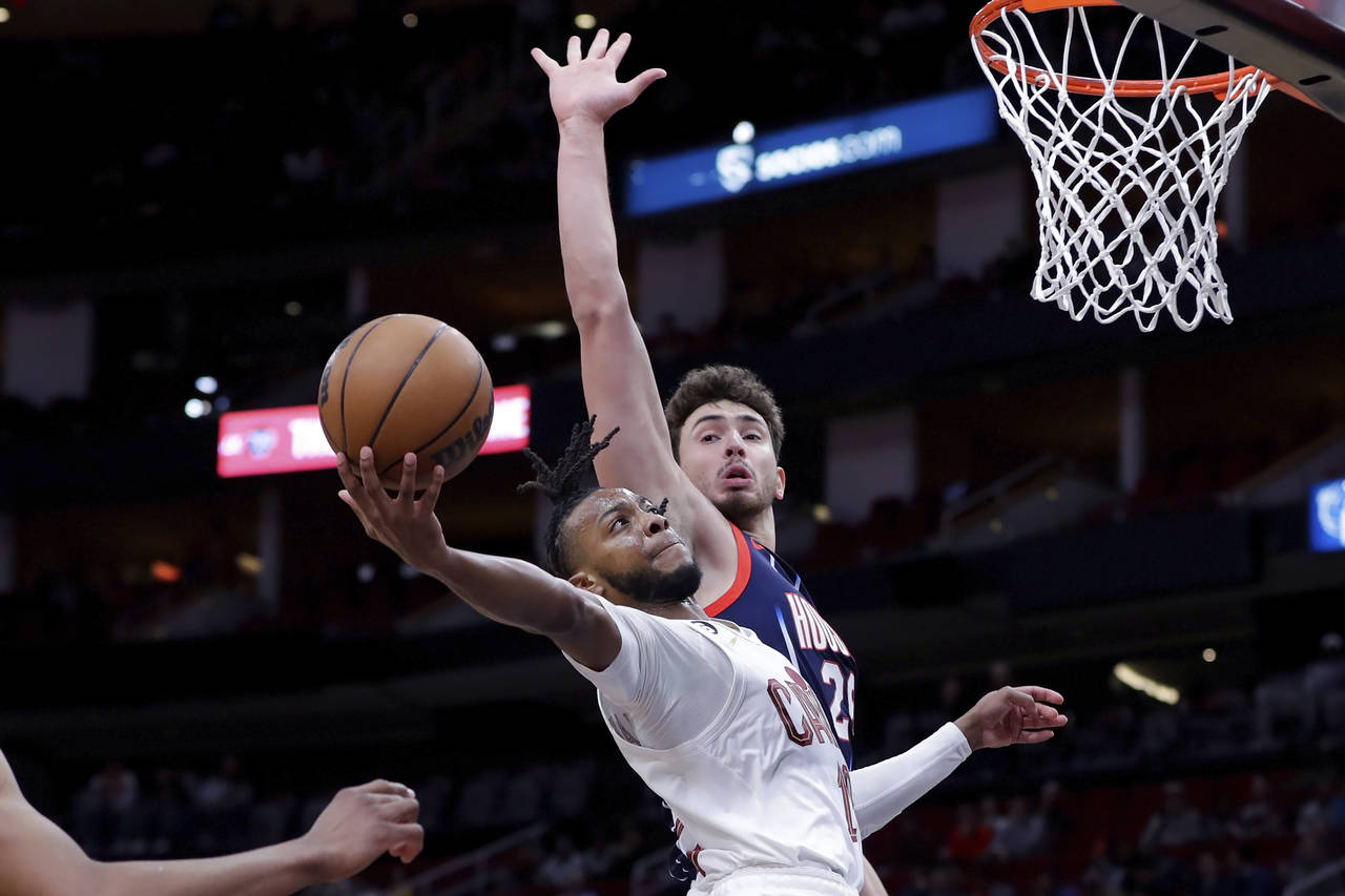 Cleveland Cavaliers guard Darius Garland, left, lays up a shot past Houston Rockets center Alperen ...