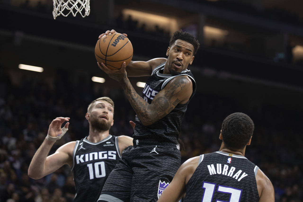 Sacramento Kings guard Malik Monk, top, pulls down a rebound between forward Domantas Sabonis (10) ...