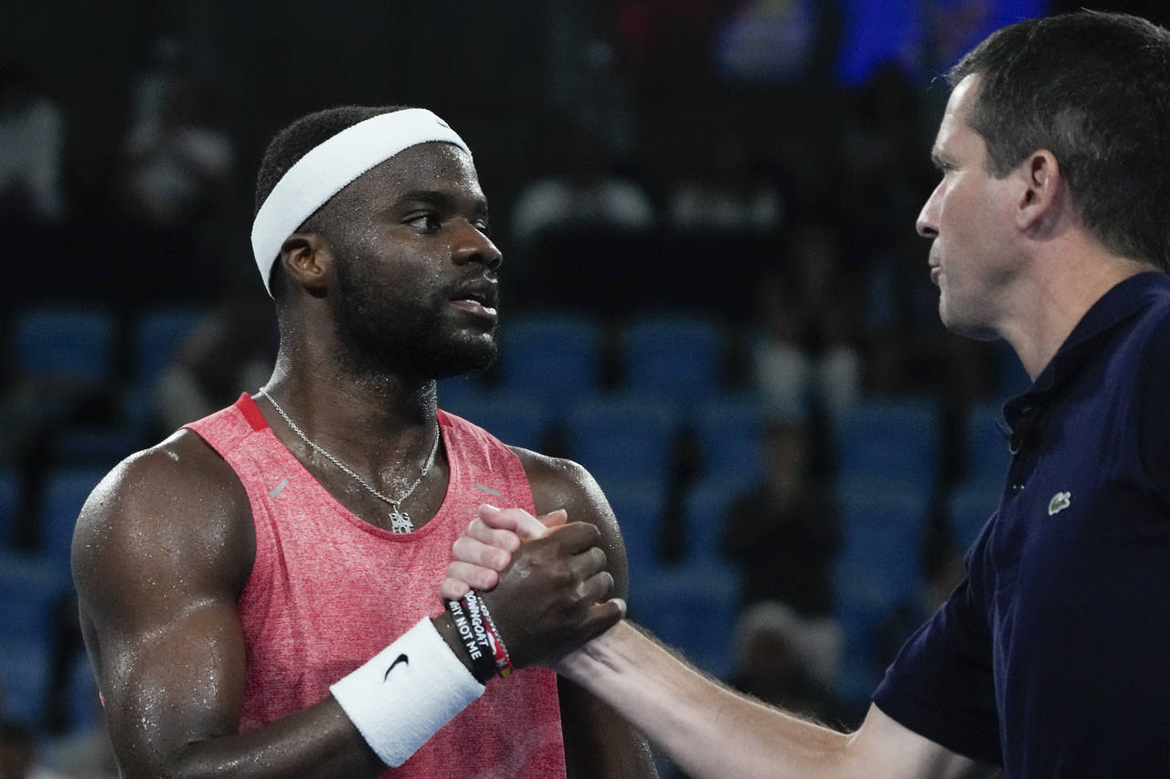 United States' Frances Tiafoe, left, is congratulated by Great Britain's team captain Tim Henman af...
