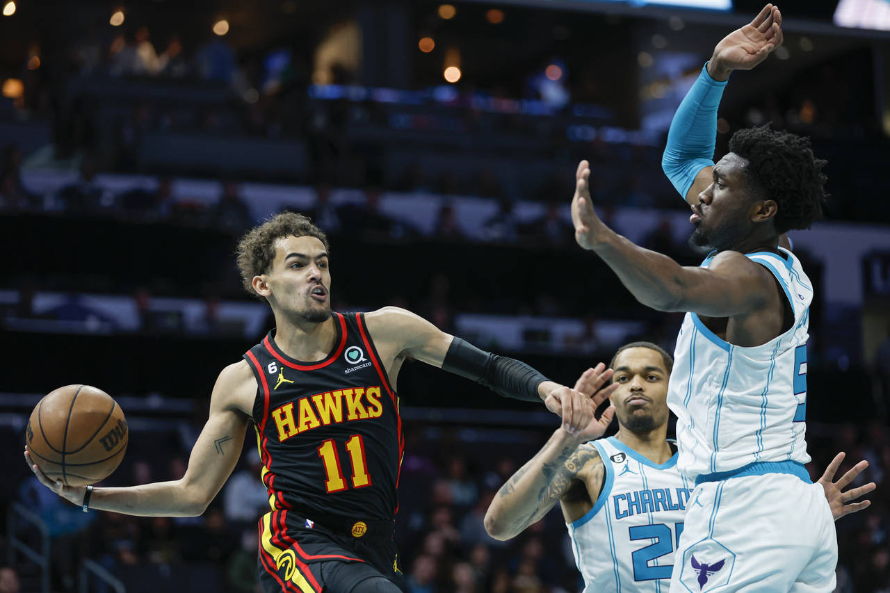 Atlanta Hawks guard Trae Young (11) passes the ball around Charlotte Hornets center Mark Williams a...