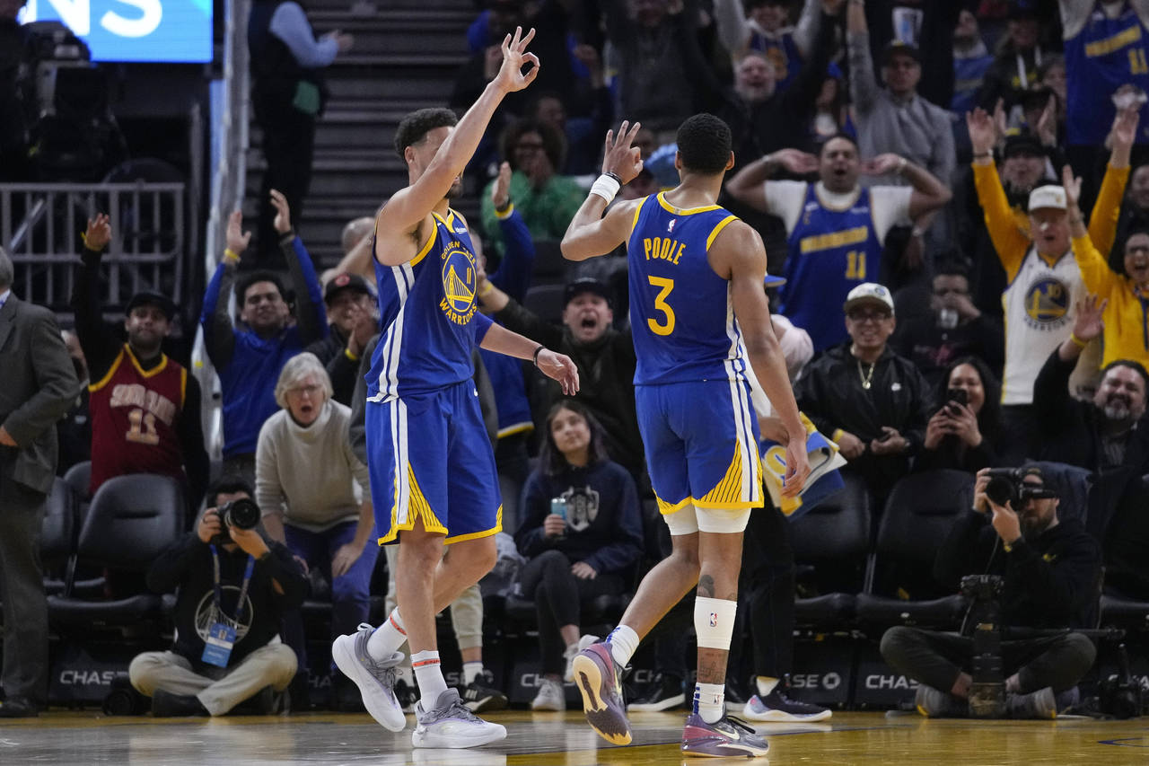 Golden State Warriors guard Jordan Poole (3) celebrates with Klay Thompson, left, after scoring a 3...