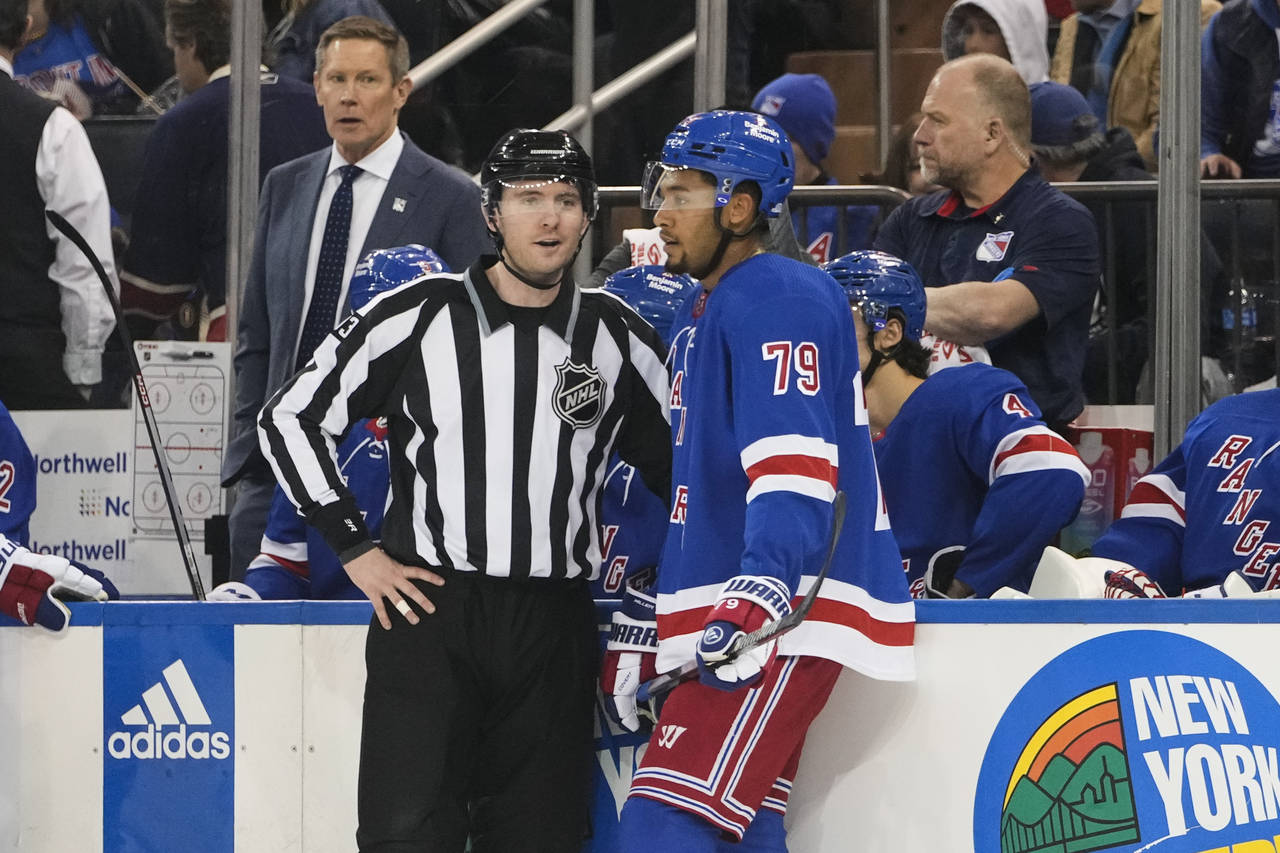 Linesman Kilian McNamara, left, talks to New York Rangers' K'Andre Miller (79) after Miller receive...