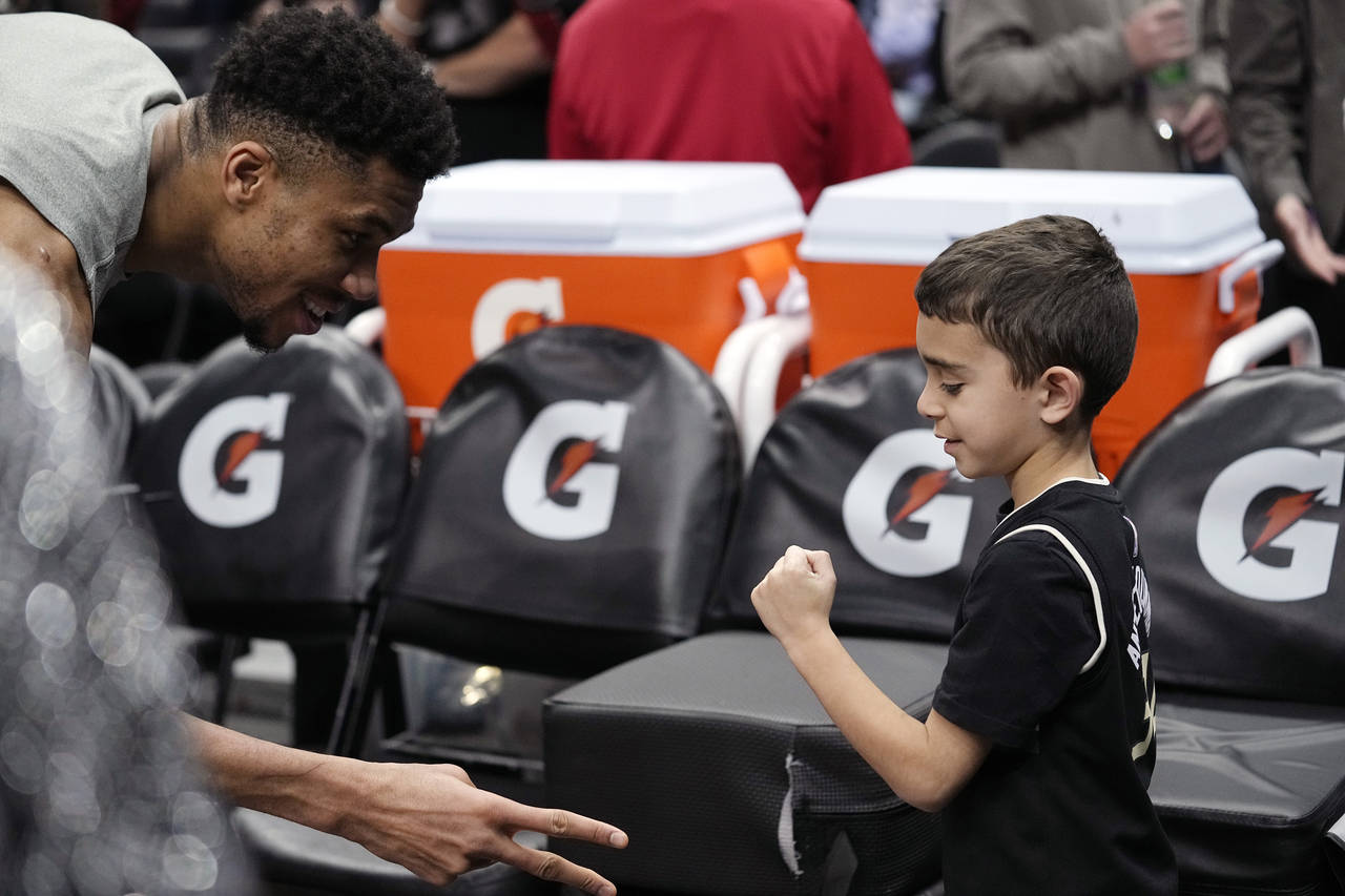 Milwaukee Bucks forward Giannis Antetokounmpo, left, plays Rock Paper Scissors with a young fan to ...
