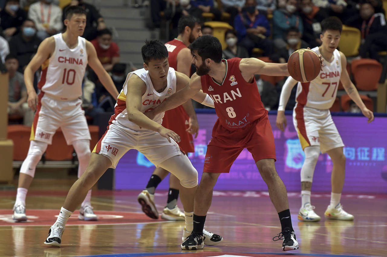 In this photo released by Xinhua News Agency, Behnam Yakhchali of Iran, right, tries to get past Zh...