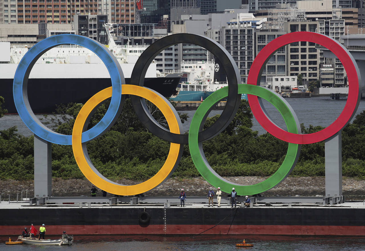 FILE - Workers prepare to remove giant Olympic rings from the waterfront area at Odaiba Marine Park...