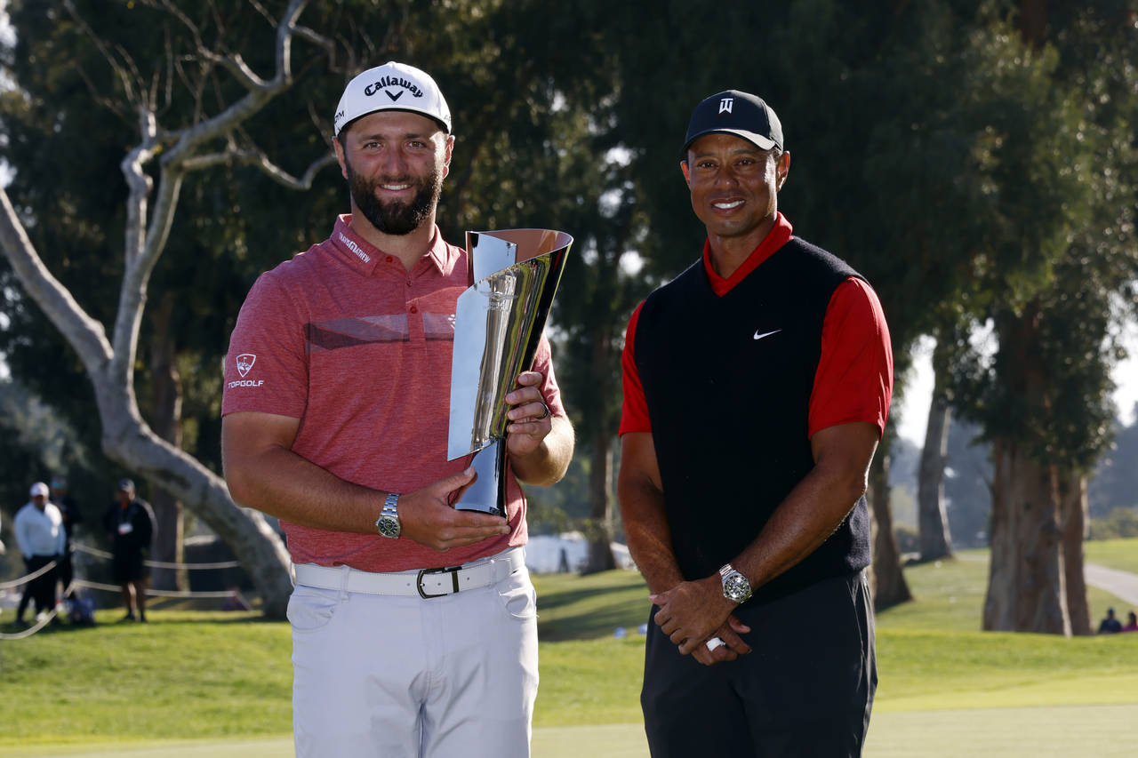 Jon Rahm, left, holds the winner's trophy next to Tiger Woods after winning the Genesis Invitationa...