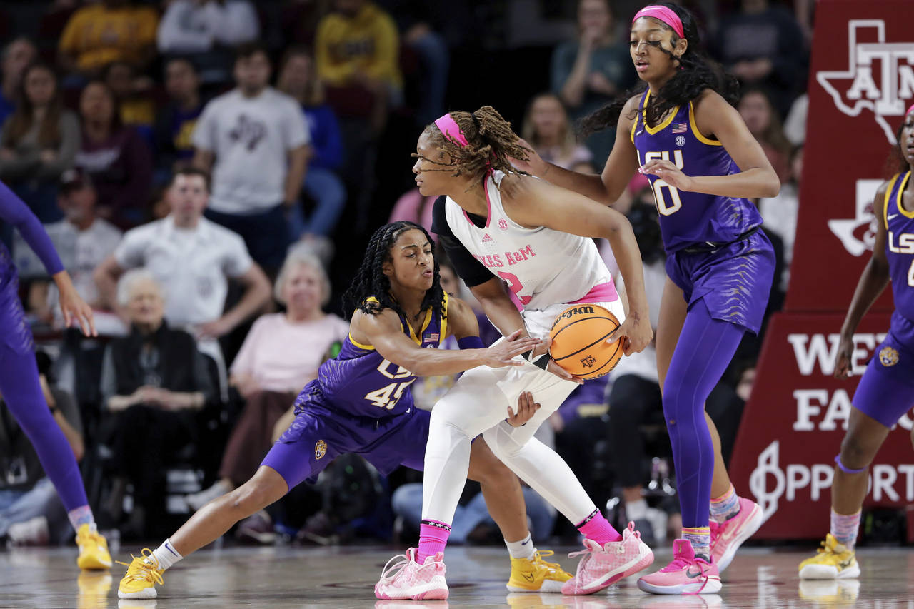 Texas A&M forward Janiah Barker, center, protects the ball as LSU guard Alexis Morris, left, reache...
