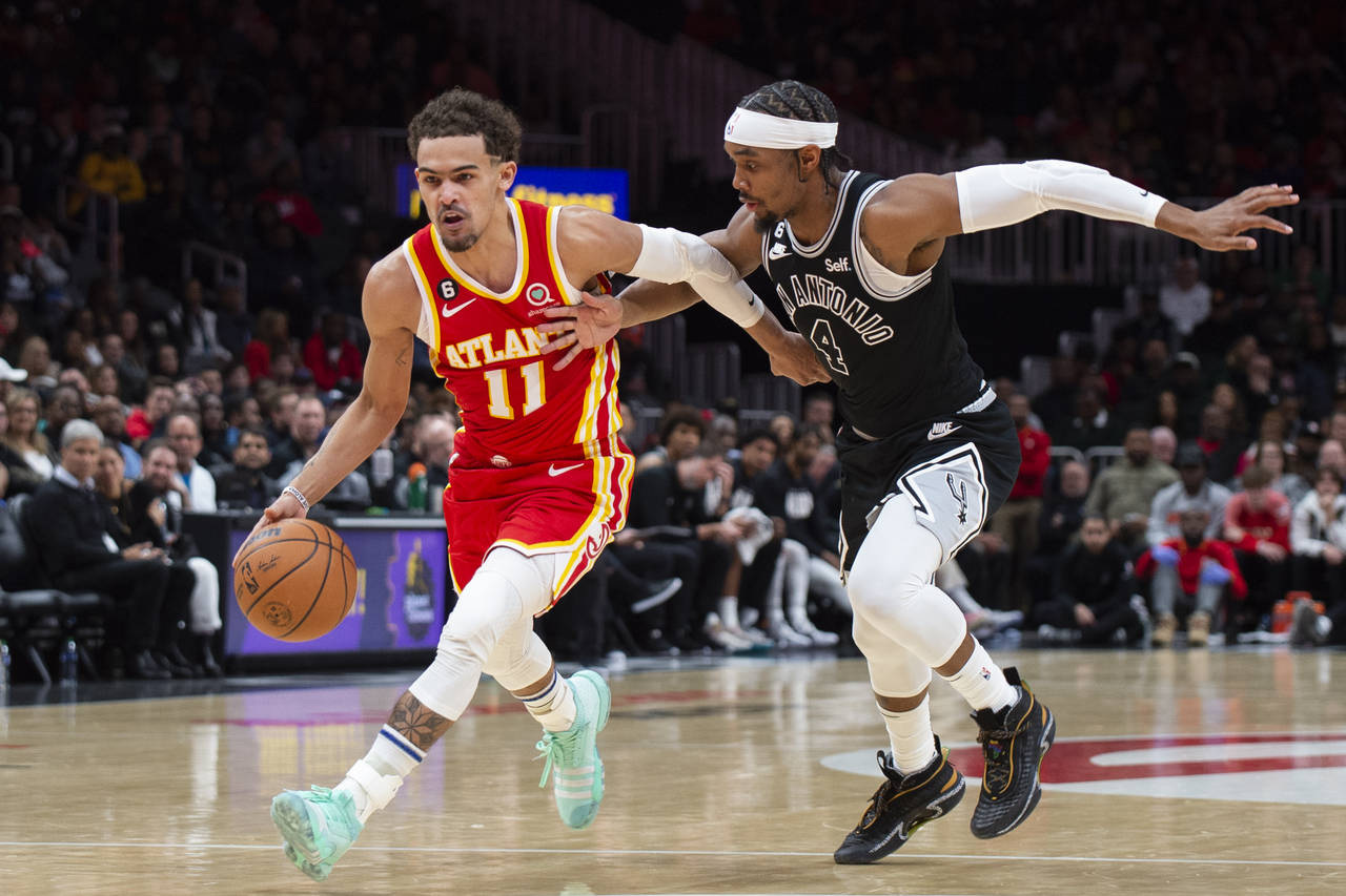 Atlanta Hawks guard Trae Young dribbles past San Antonio Spurs guard Devonte' Graham during the fir...