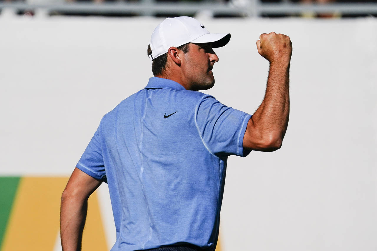 Scottie Scheffler pumps his fist after making par on the 16th hole of the final round of the Phoeni...