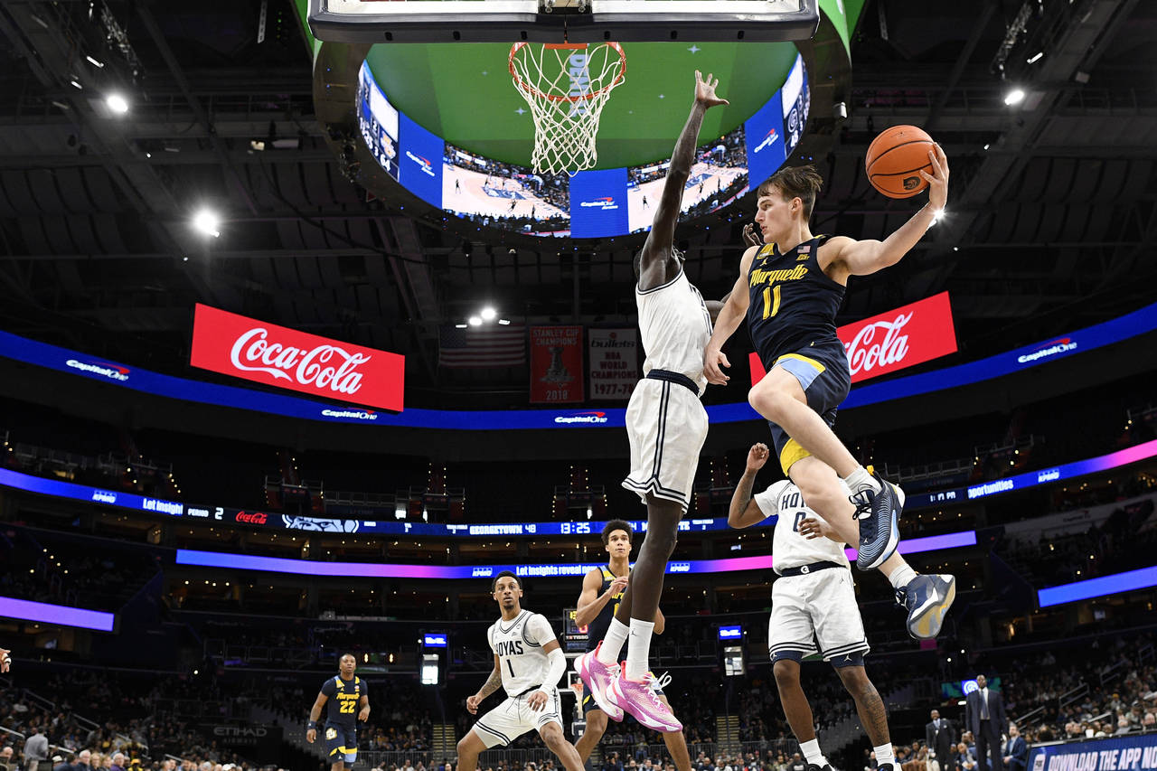 Marquette guard Tyler Kolek (11) goes to the basket against Georgetown forward Akok Akok, center, d...