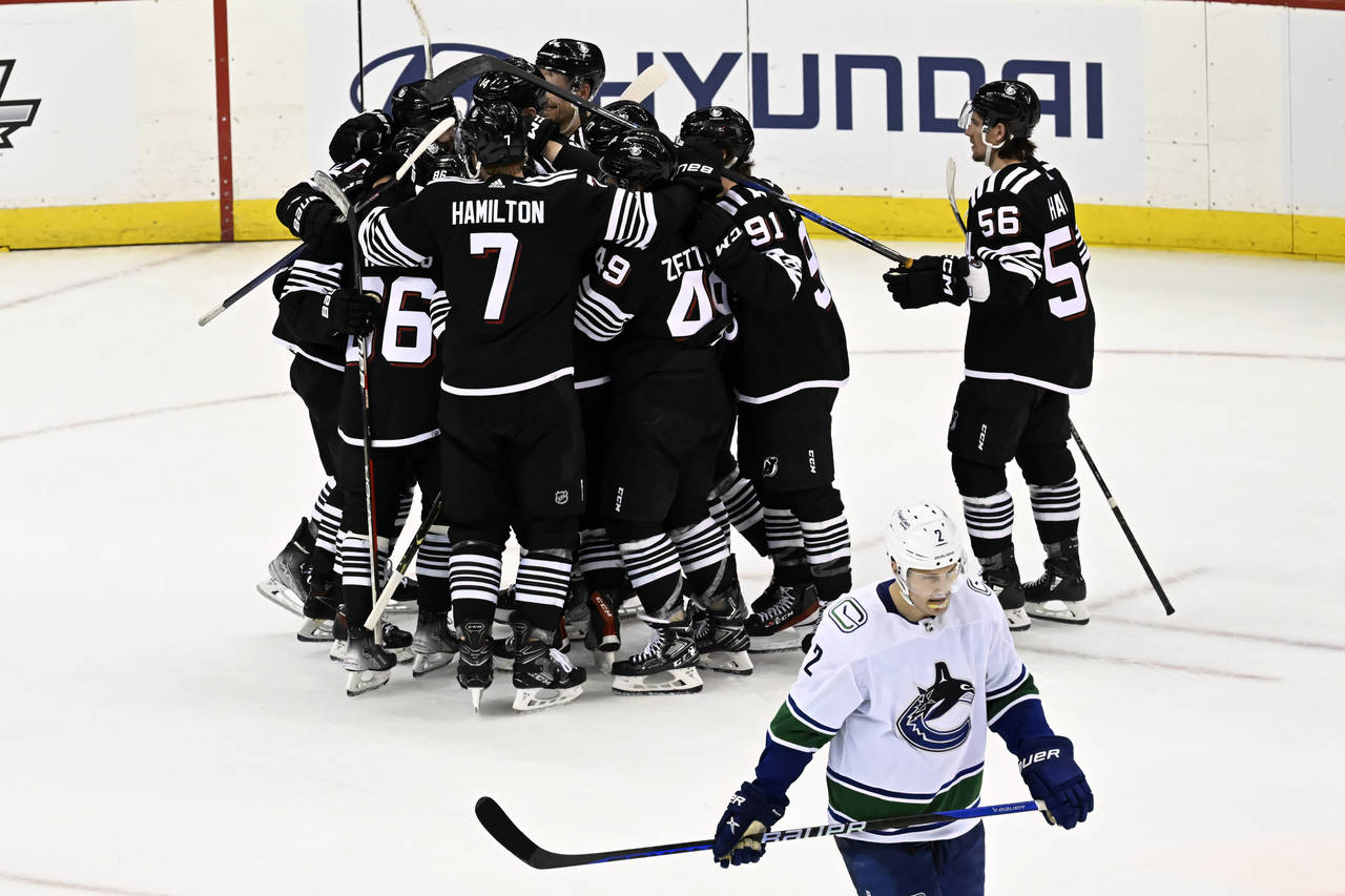 The New Jersey Devils surround Jesper Bratt after his winning goal as Vancouver Canucks defenseman ...