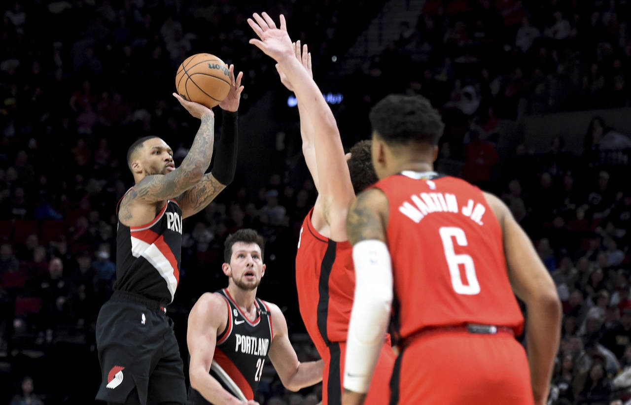 Portland Trail Blazers guard Damian Lillard, left, hits a 3-point shot over Houston Rockets forward...