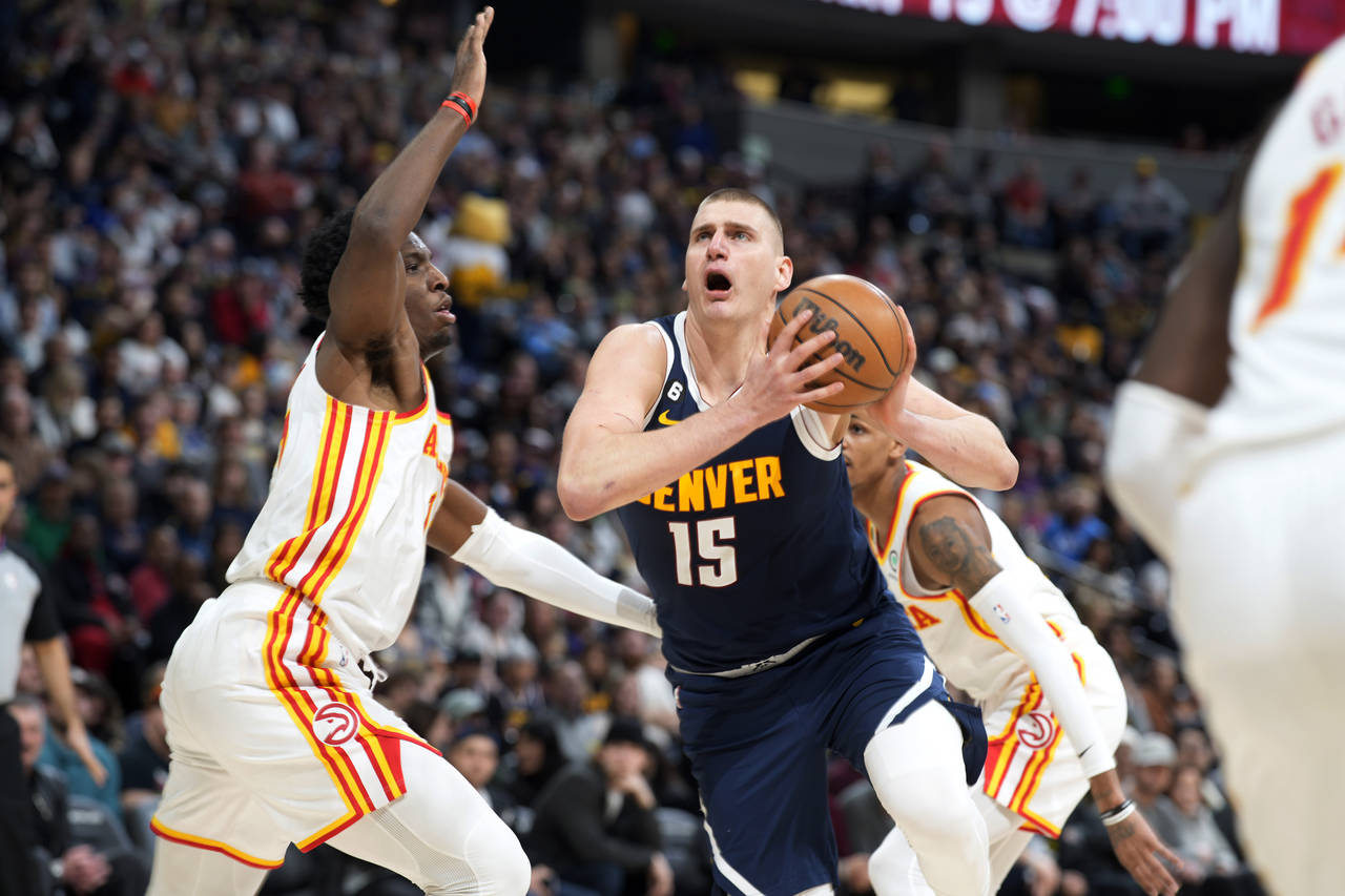 Denver Nuggets center Nikola Jokic, right, drives to the rim as Atlanta Hawks forward Onyeka Okongw...