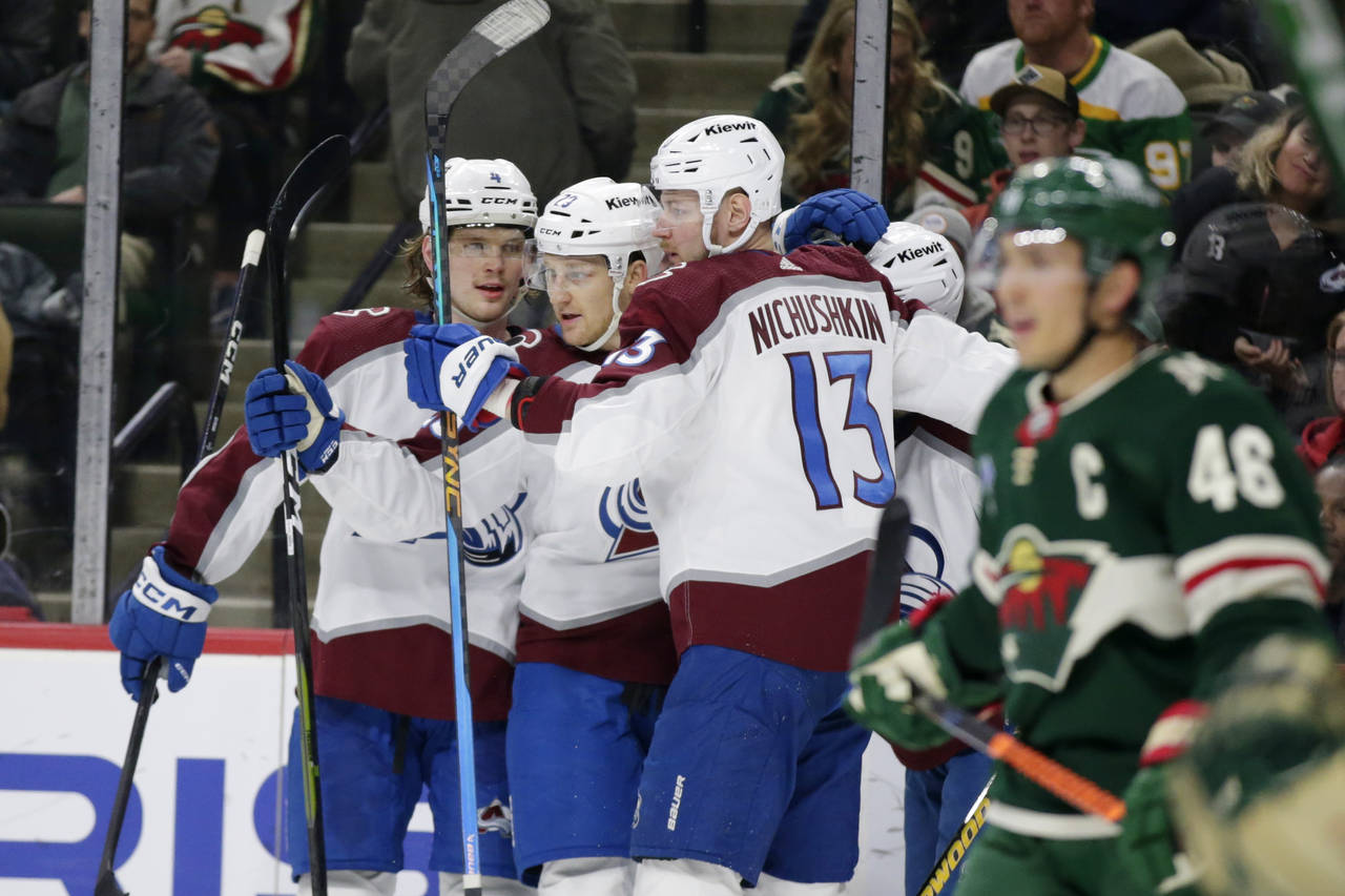 Colorado Avalanche's Nathan MacKinnon (29) is congratulated by Bowen Byram (4) and Valeri Nichushki...