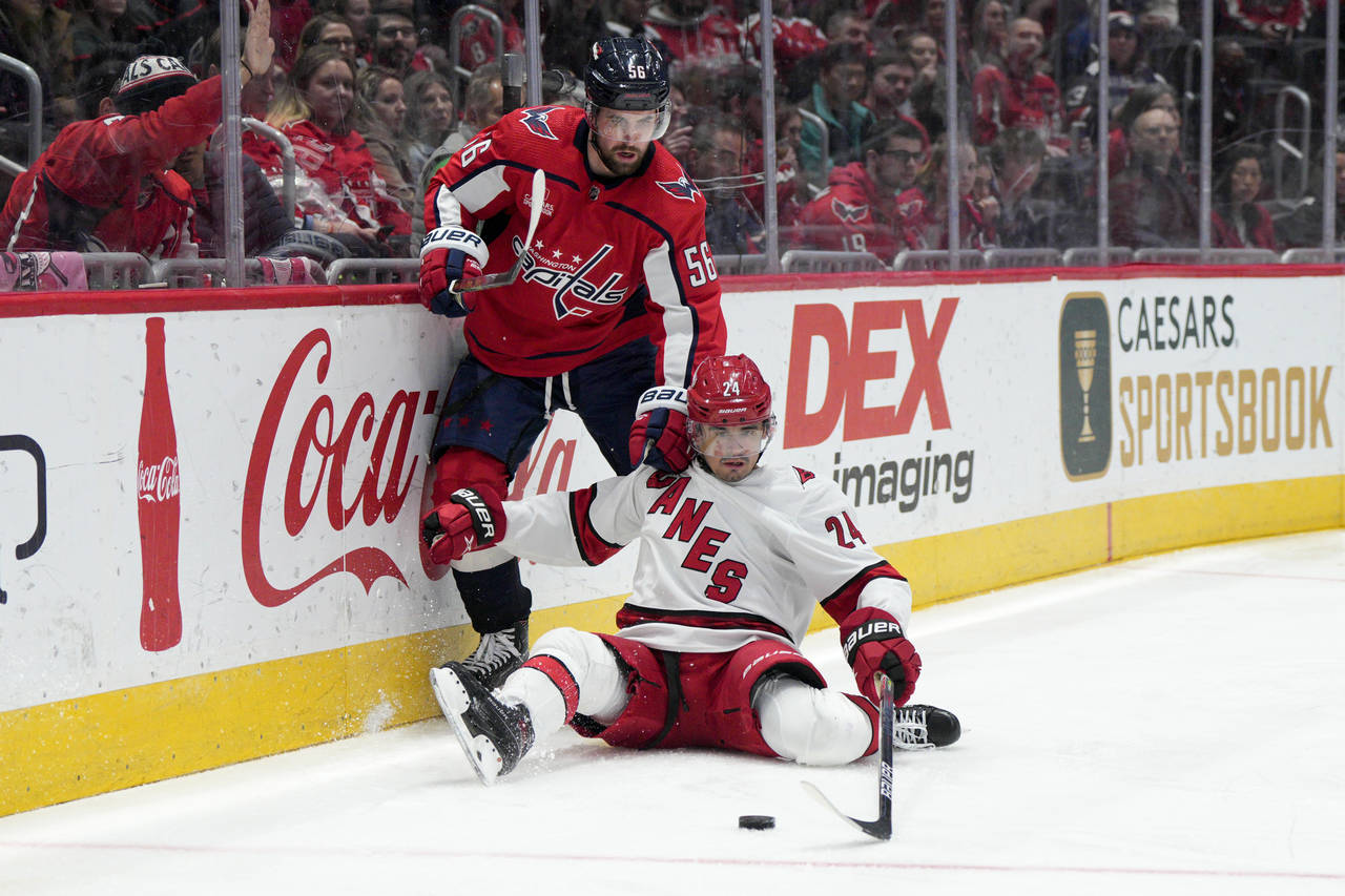 Carolina Hurricanes center Seth Jarvis (24) reaches for the puck as Washington Capitals defenseman ...