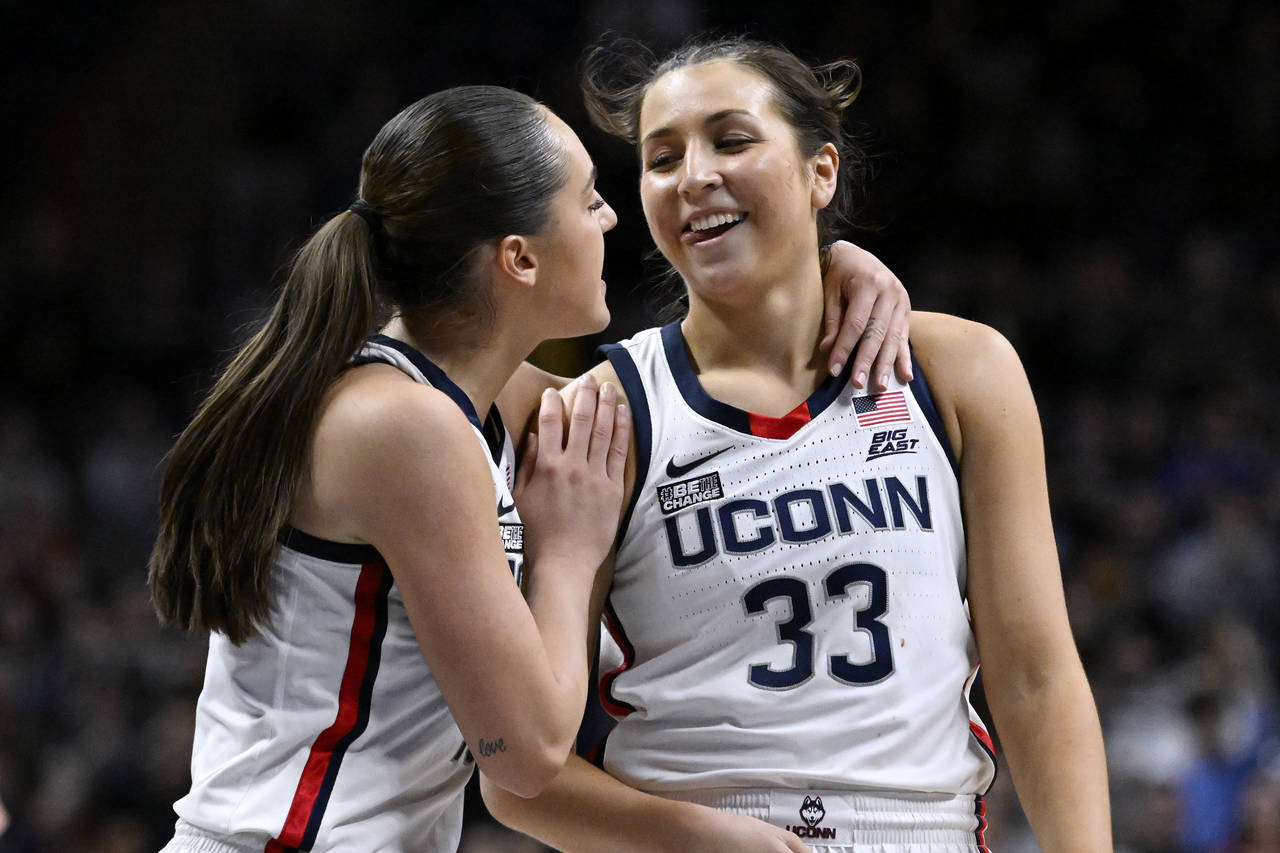 UConn's Nika Muhl, left, congratulates Caroline Ducharme (33), who made the go-ahead basket in the ...