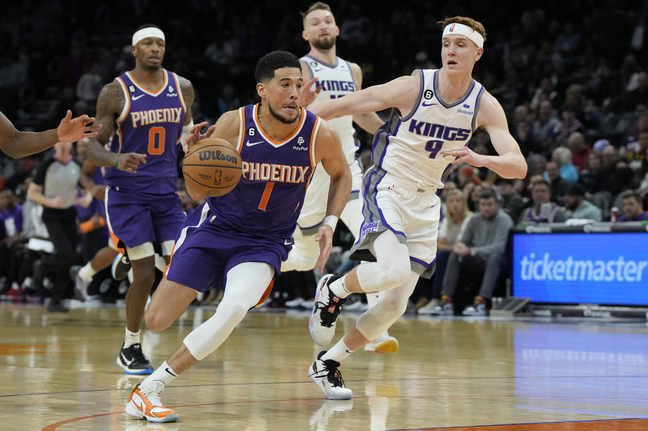 Phoenix Suns guard Devin Booker (1) drives past Sacramento Kings guard Kevin Huerter (9) during the...
