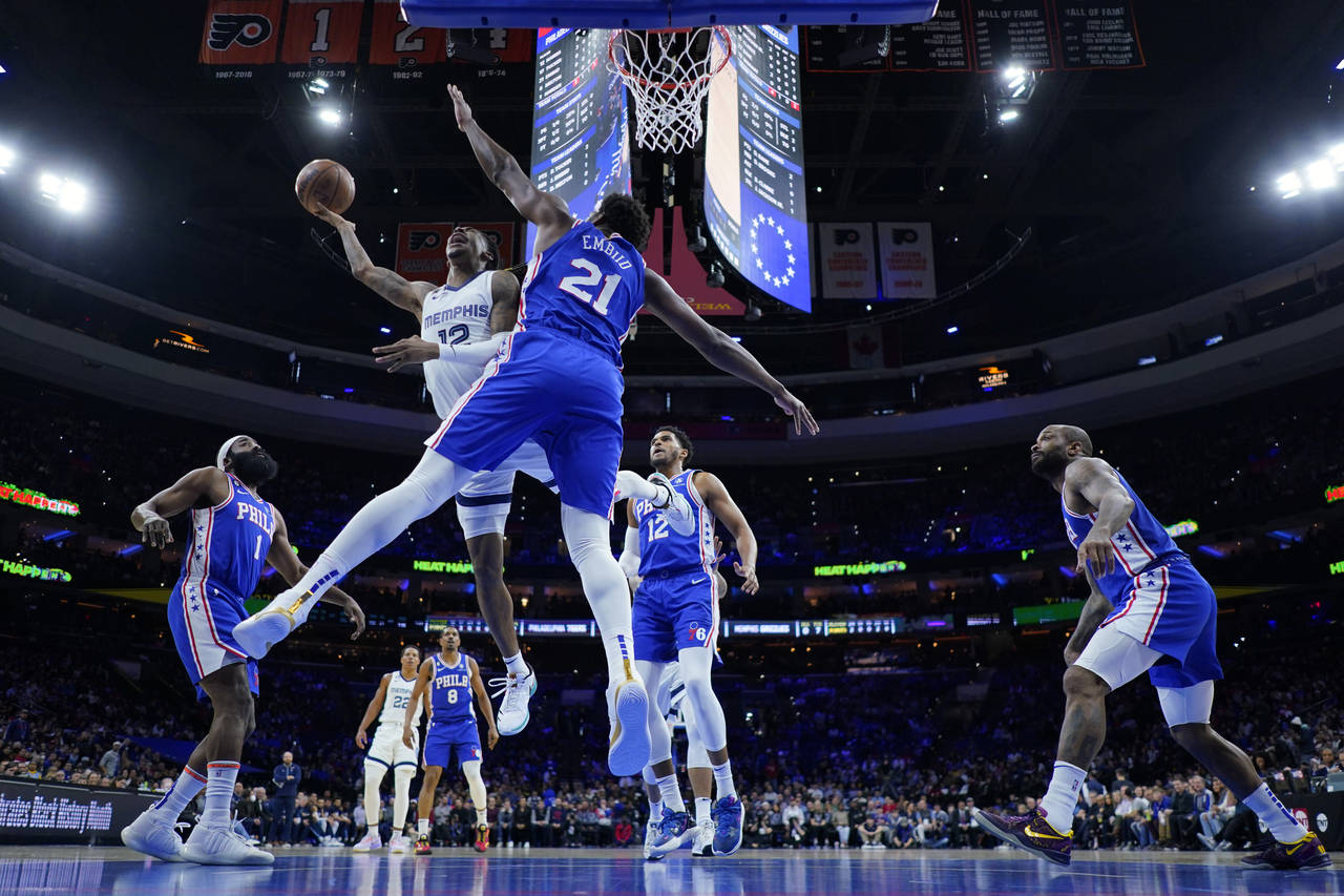 Memphis Grizzlies' Ja Morant, left, goes up for a shot against Philadelphia 76ers' Joel Embiid duri...